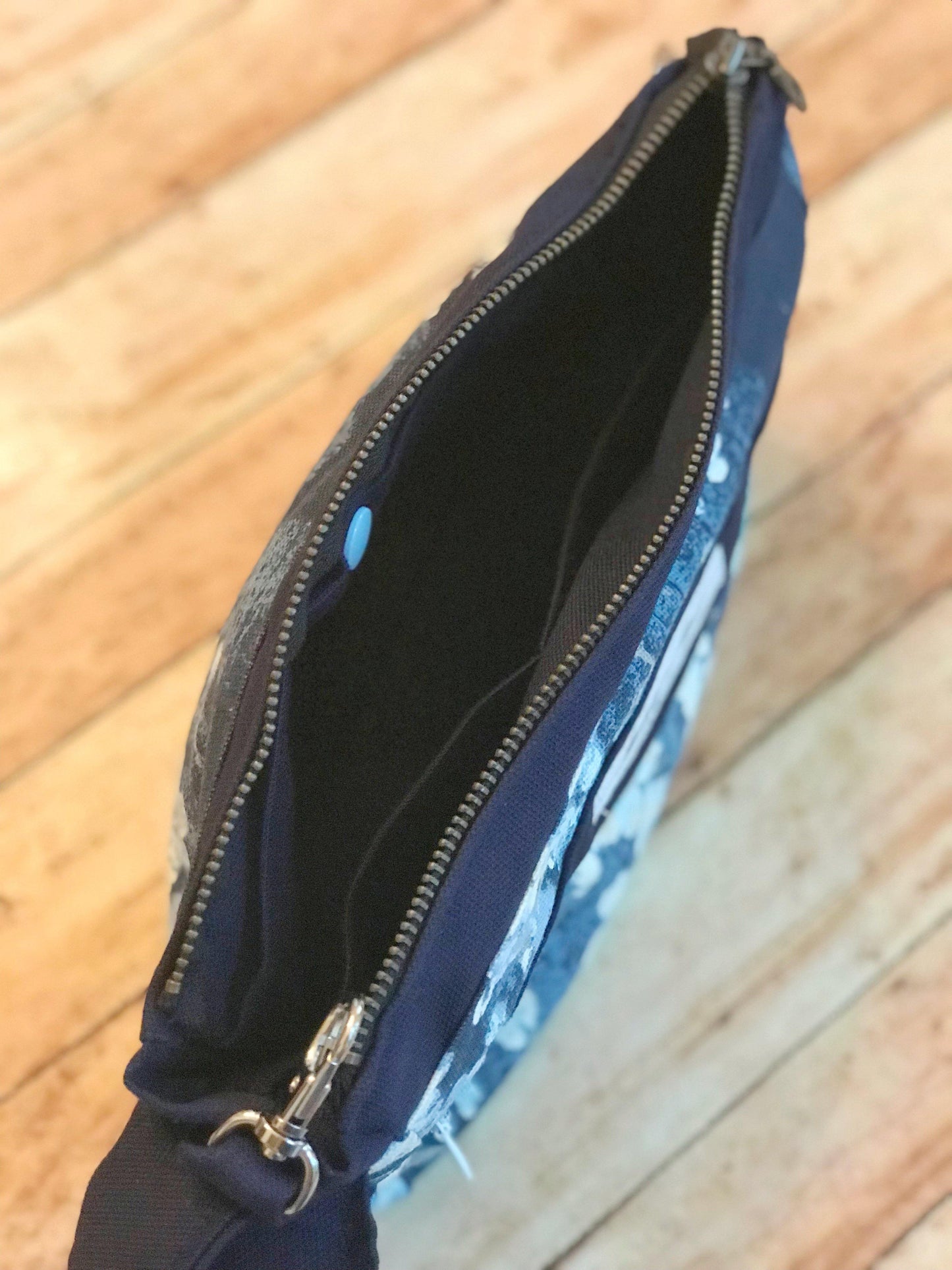 Inside view of blue teal floral wristlet, showing a divided pocket on one side & snap pocket on the other