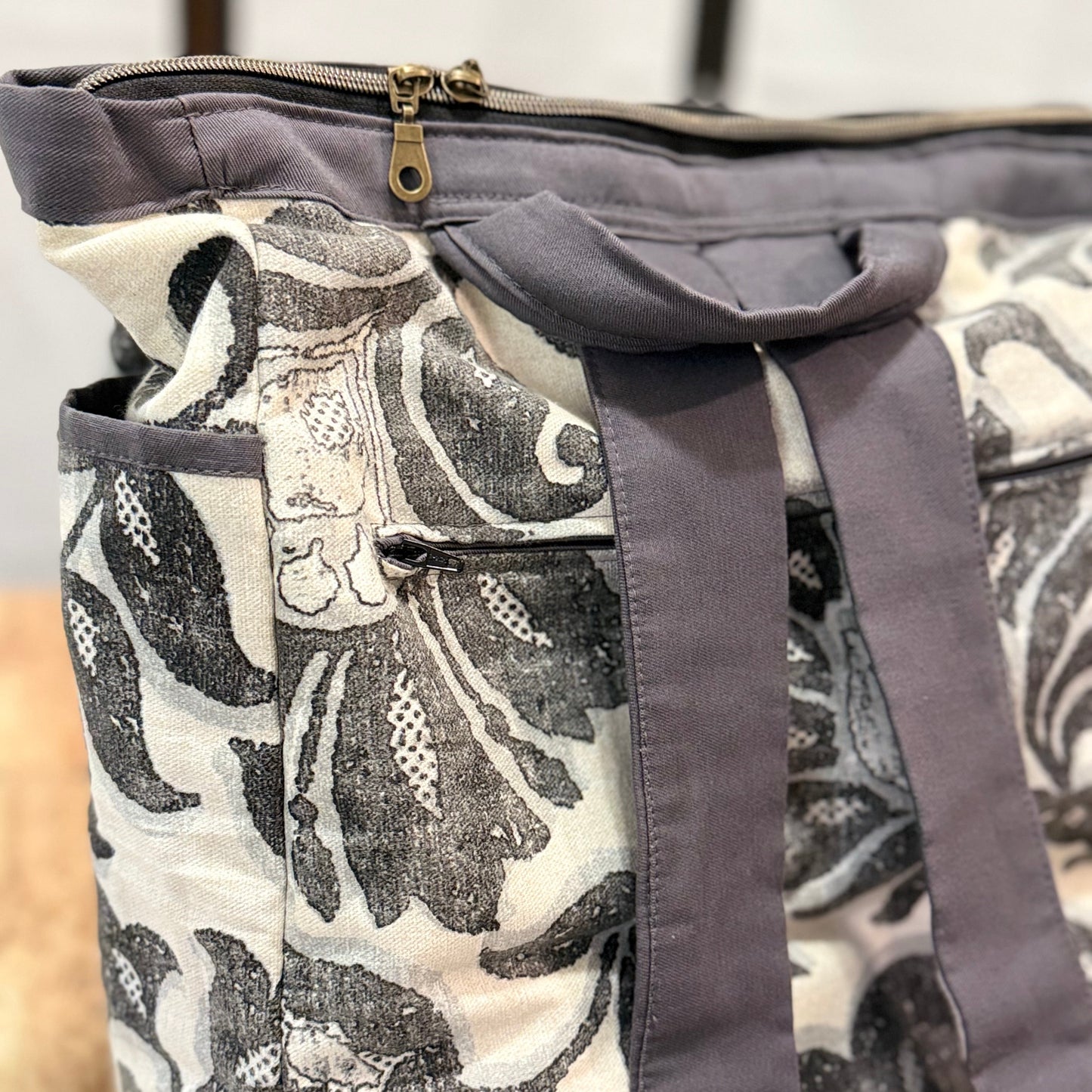 Gray bag with black floral pattern on a wooden surface