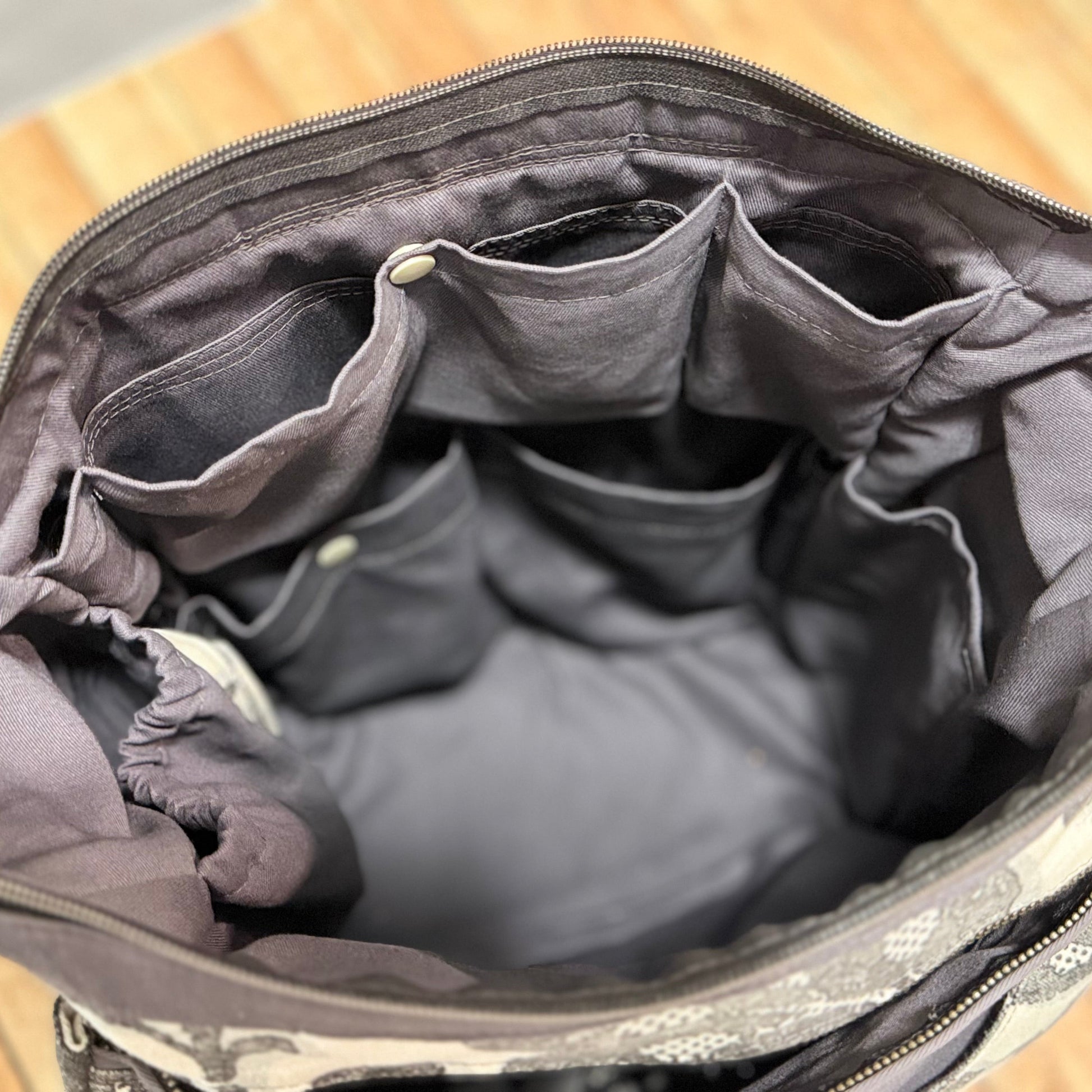 Open gray bag with floral pattern on a wooden surface